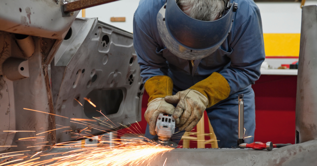 Auto worker using tools on metal car parts